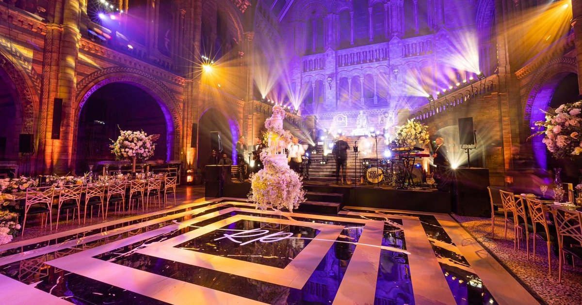 Matt gold monogram printed dance floor on piano black sheets under the arches of the Natural History Museum, London