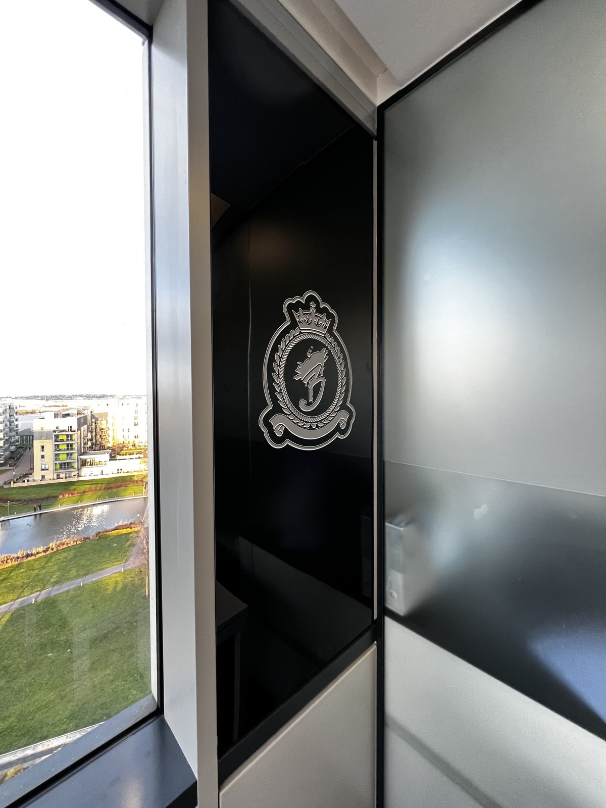 The crest on a black glass panel beside the floor to ceiling windows