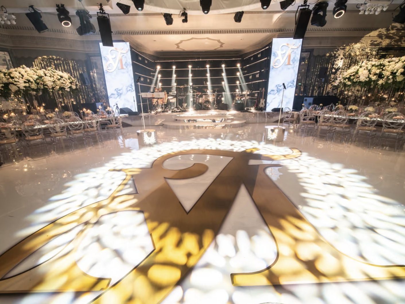 Gloss white printed dance floor with a giant gold monogram at The Dorchester