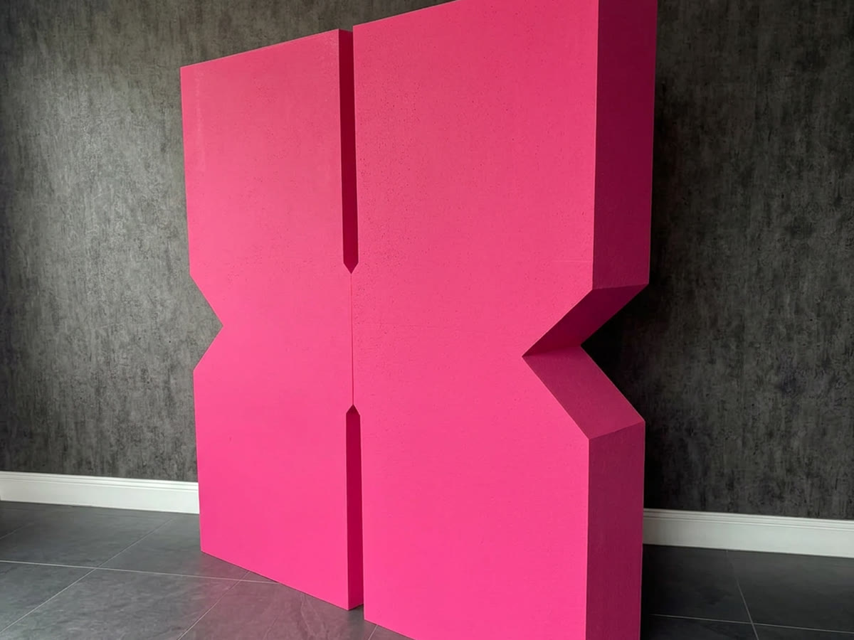 Giant pink CNC cut 3D foam letter standing in a studio