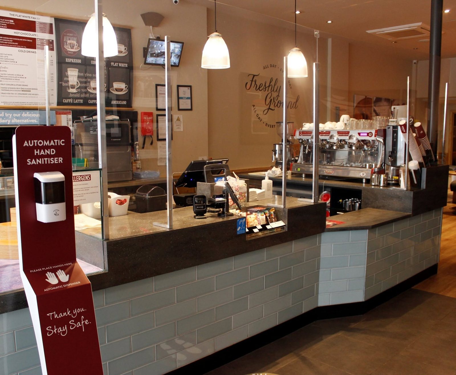 Made to measure metal framed Perspex screens on a Costa Coffee counter, with an automatic hand sanitiser station
