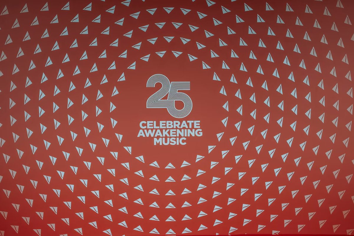 Printed red Celebrate Awakening Music 25 backdrop with a radiating white triangle pattern