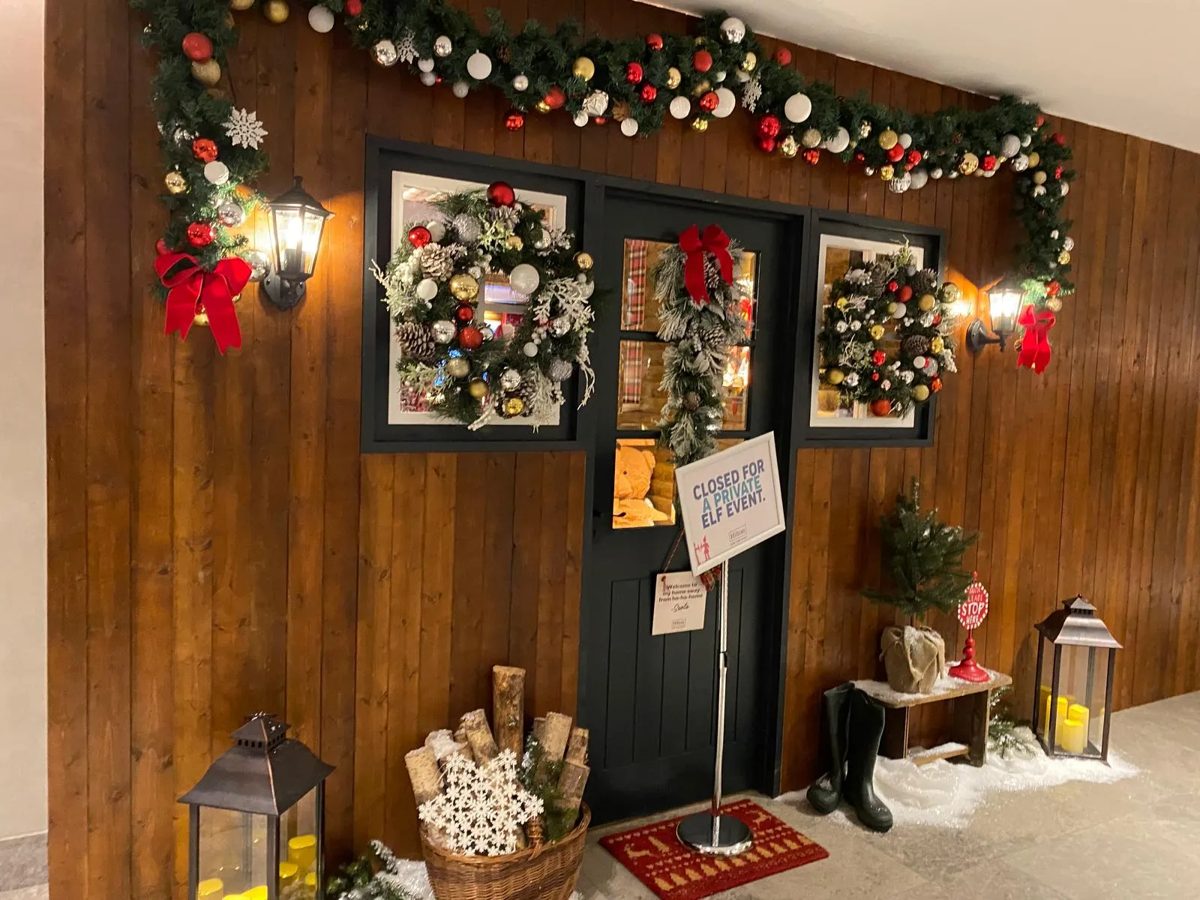 Timber cabin entrance dressed with garlands, wreaths and lanterns
