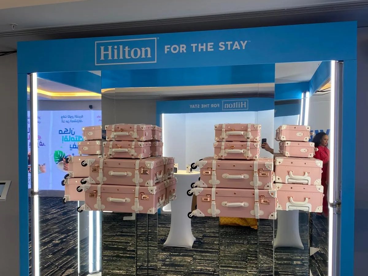 Mirrored display box stacked with pink suitcases under a Hilton header