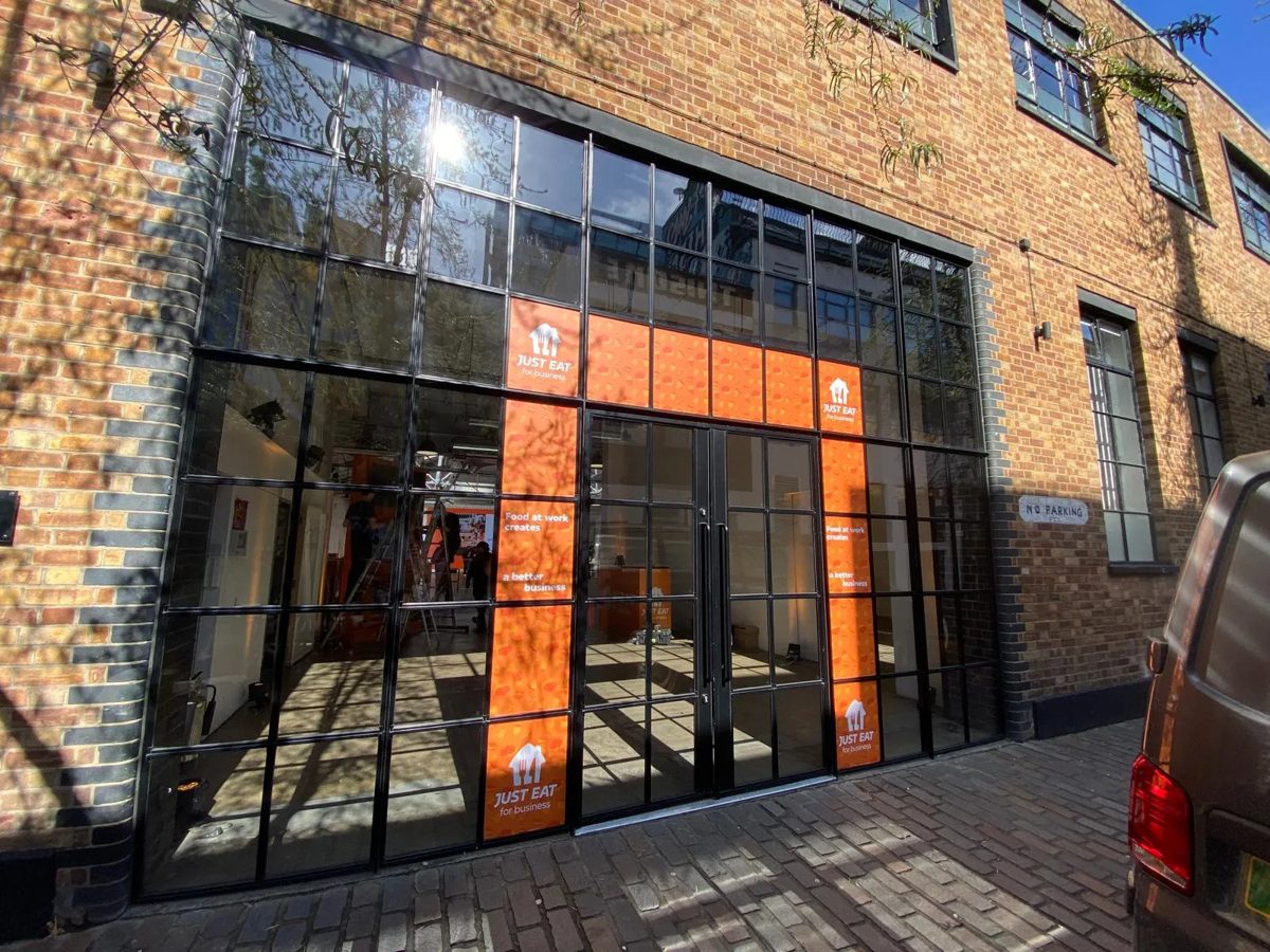 Orange Just Eat for Business window graphics framing the doors of a London warehouse venue