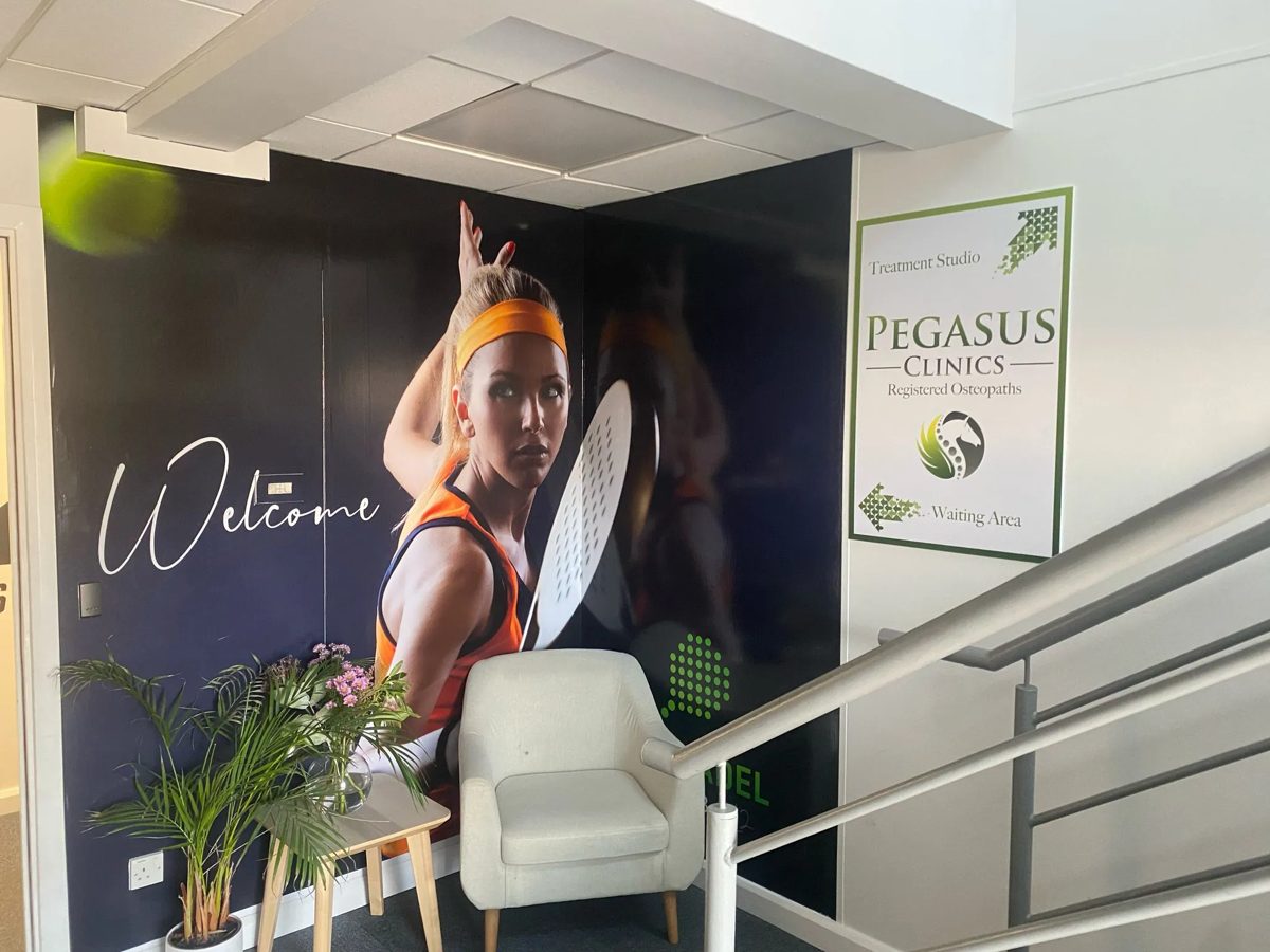 Welcome padel player wall graphic beside the Pegasus treatment studio sign