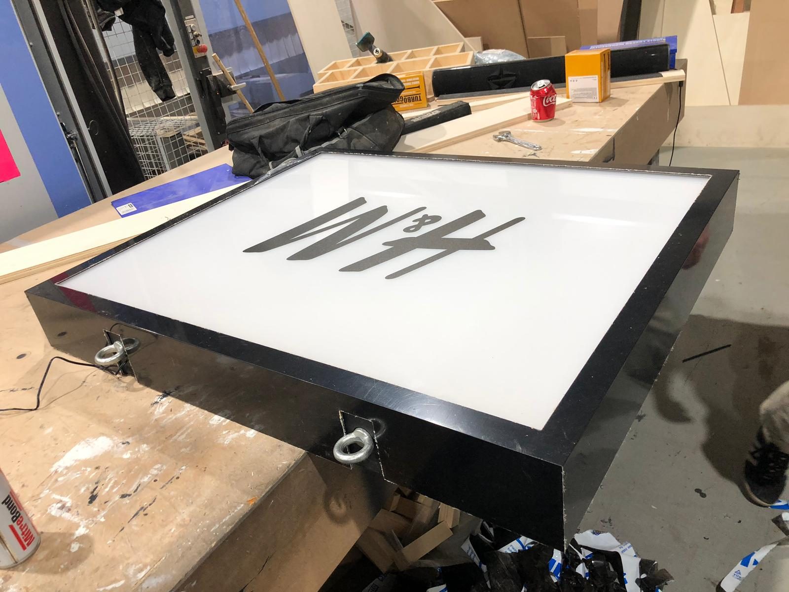An H&M lightbox fitted with eye bolts, ready to hang in the pop up