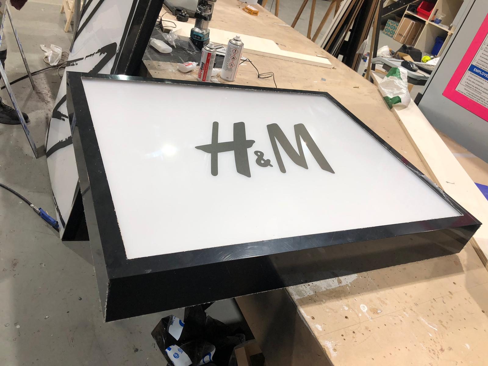 H&M lightbox with a printed acrylic face in a gloss black frame