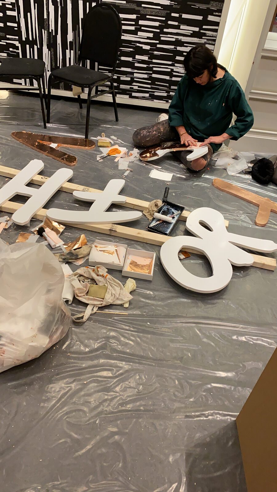 Hand finishing the CNC cut letters in a bronze metallic leaf