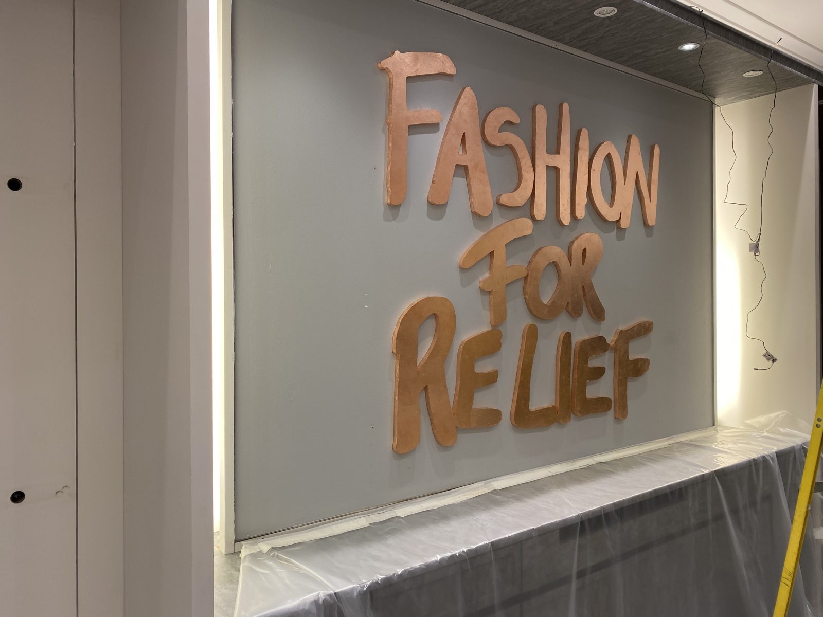 The CNC cut Fashion for Relief logo in bronze on the feature wall