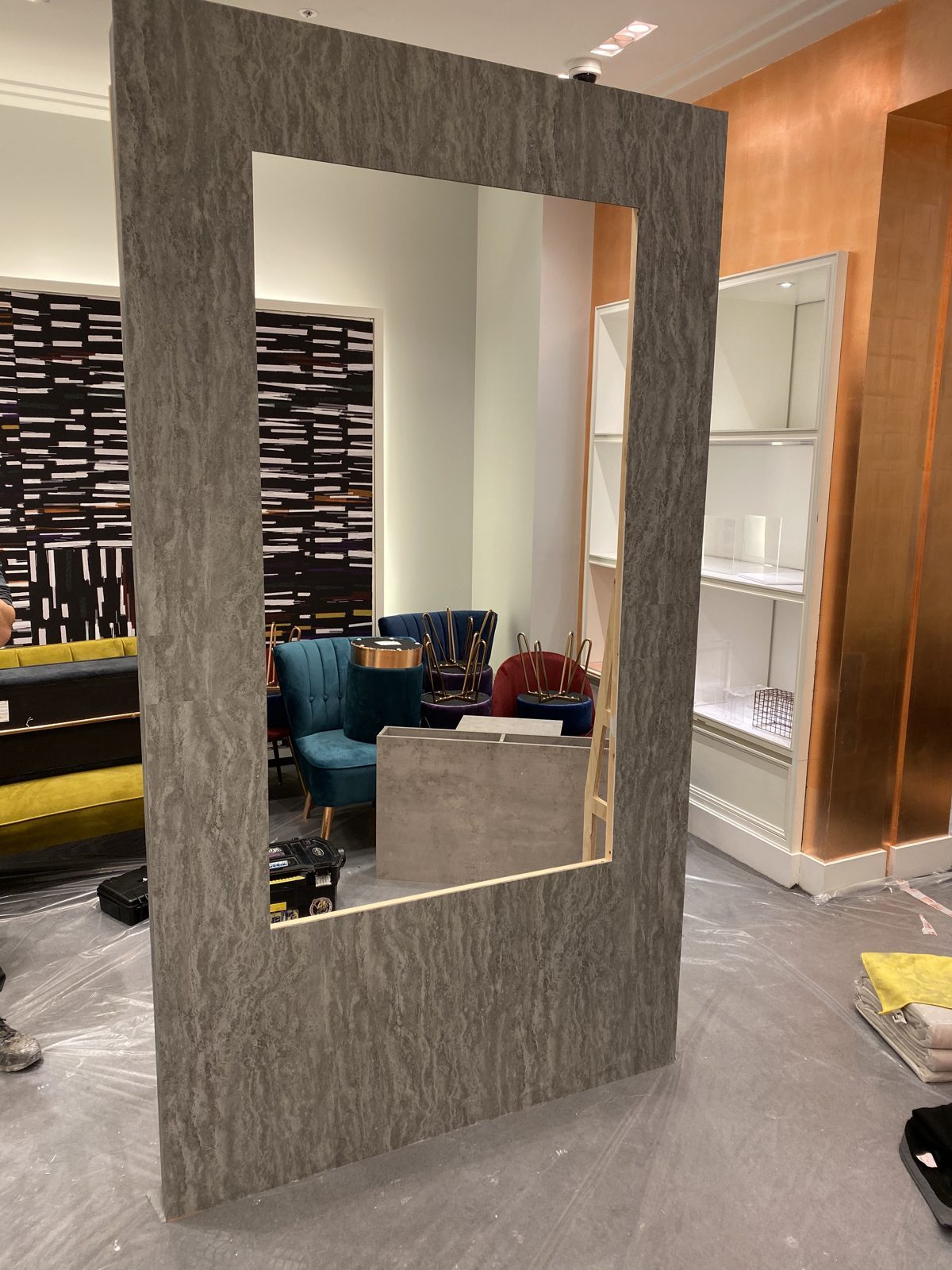 A freestanding mirror frame finished in the same grey furniture vinyl