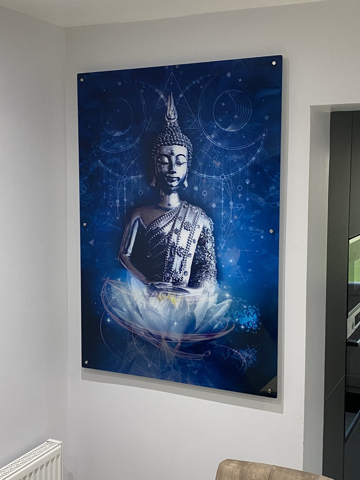 Large portrait acrylic print of a silver Buddha on a glowing blue lotus background, fixed to a white wall with stand offs