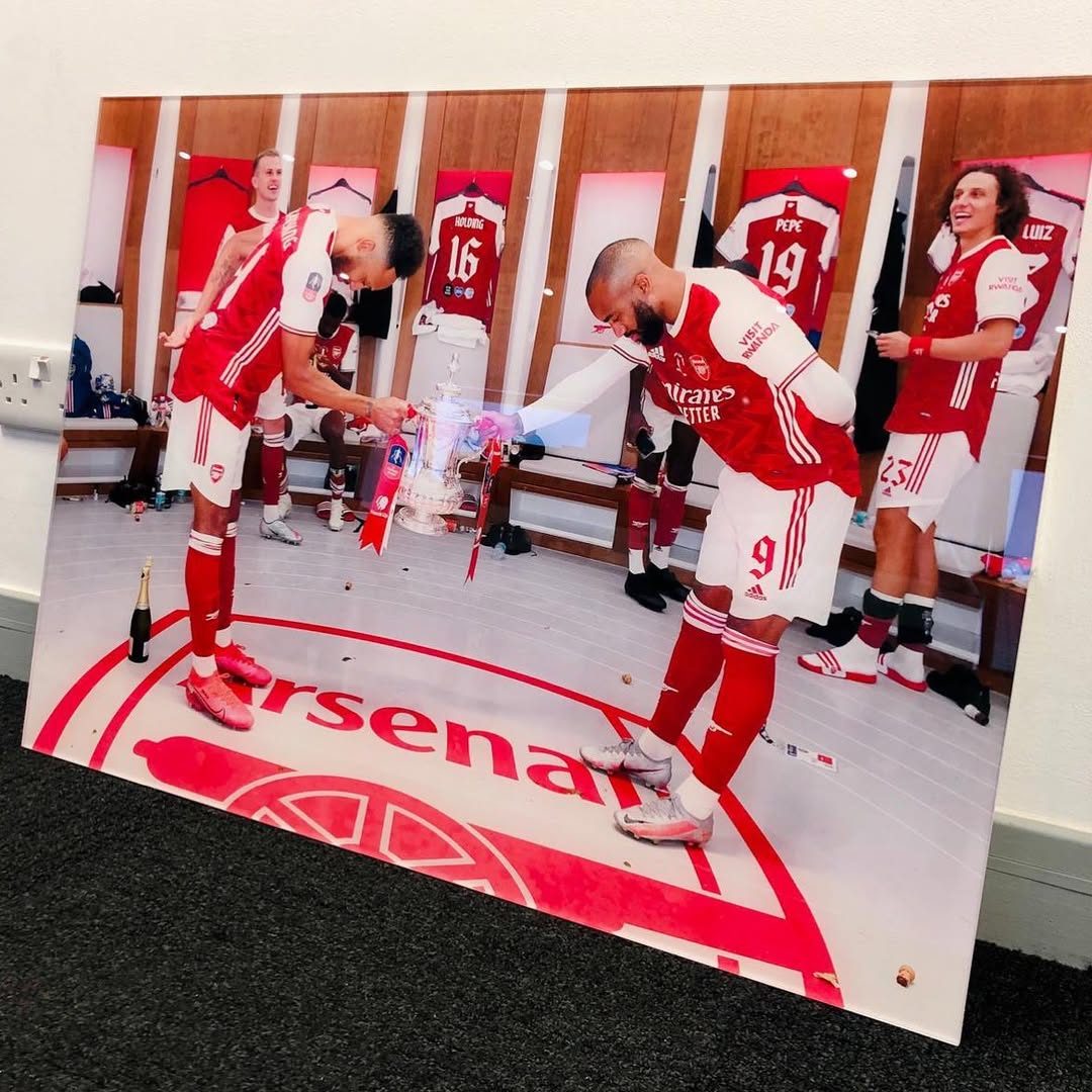 Reverse printed acrylic photo of Arsenal players celebrating with the FA Cup in the dressing room, leaning against a wall