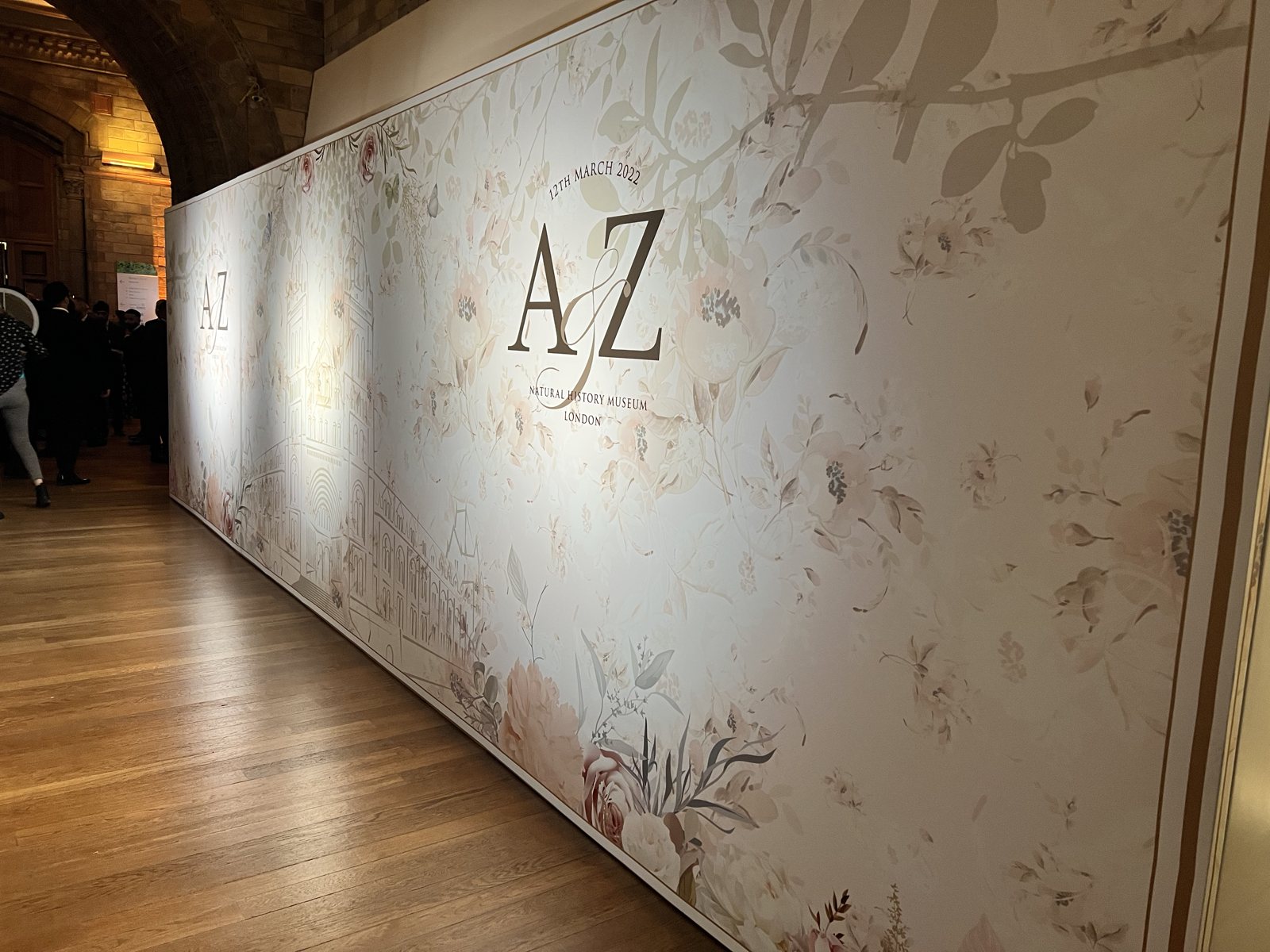 Long canvas wrapped wedding media board for A and Z at the Natural History Museum, London, with soft blush florals, birds on a branch and a line drawing of the museum