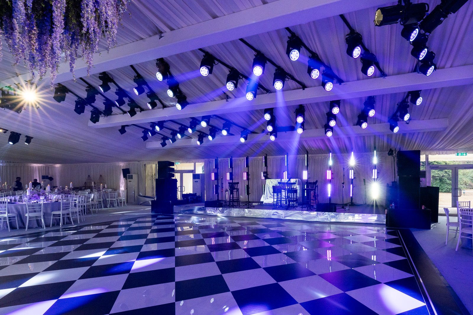 Huge black and white chequerboard printed dance floor in a marquee under purple stage lighting at a private event in Buckinghamshire
