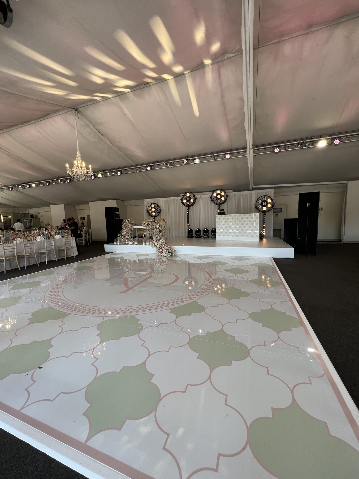 Bespoke printed wedding dance floor in sage green and blush with a monogram, and a matching white DJ booth in a marquee
