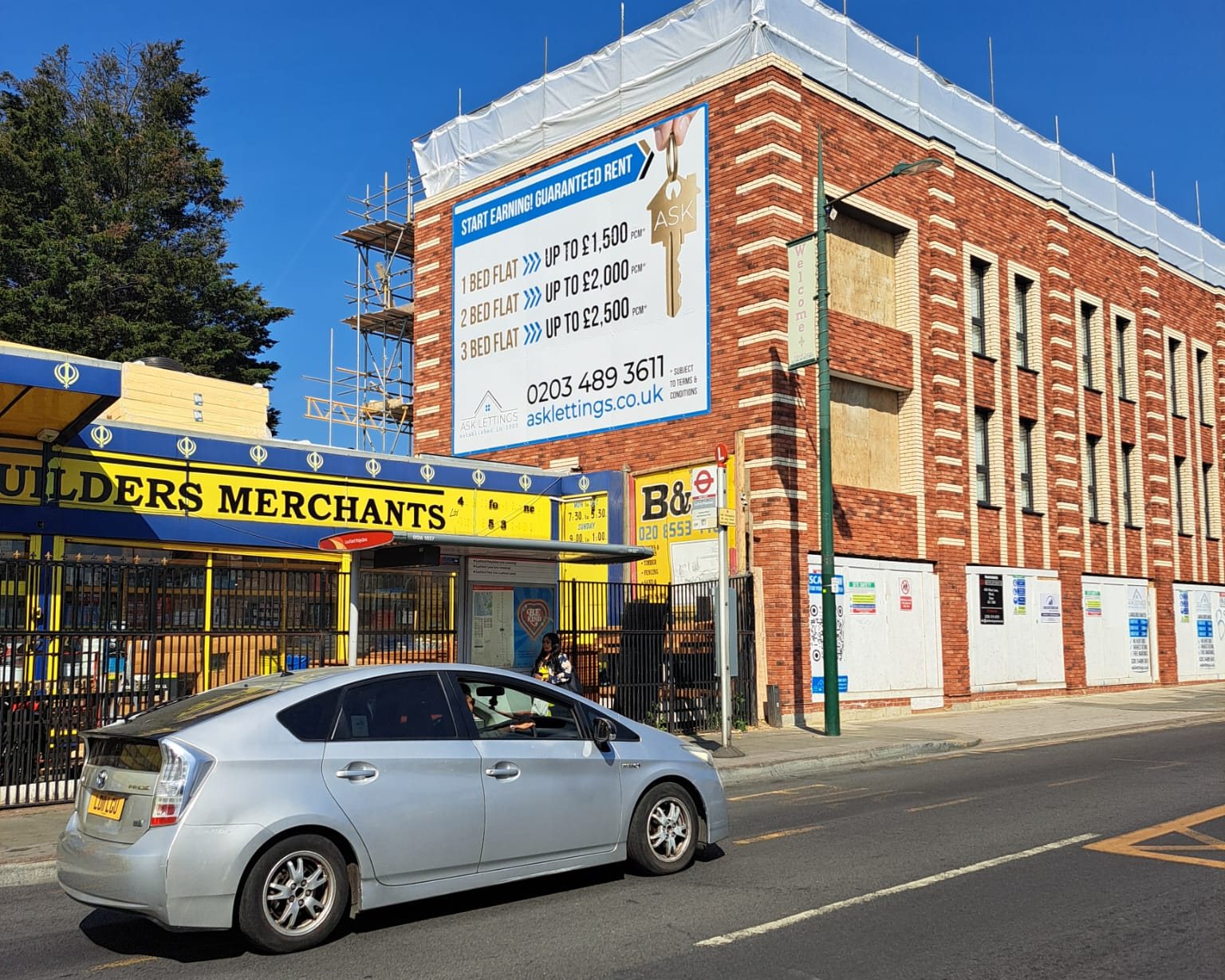 Large ASK Lettings guaranteed rent board mounted high on a new brick building in Ilford