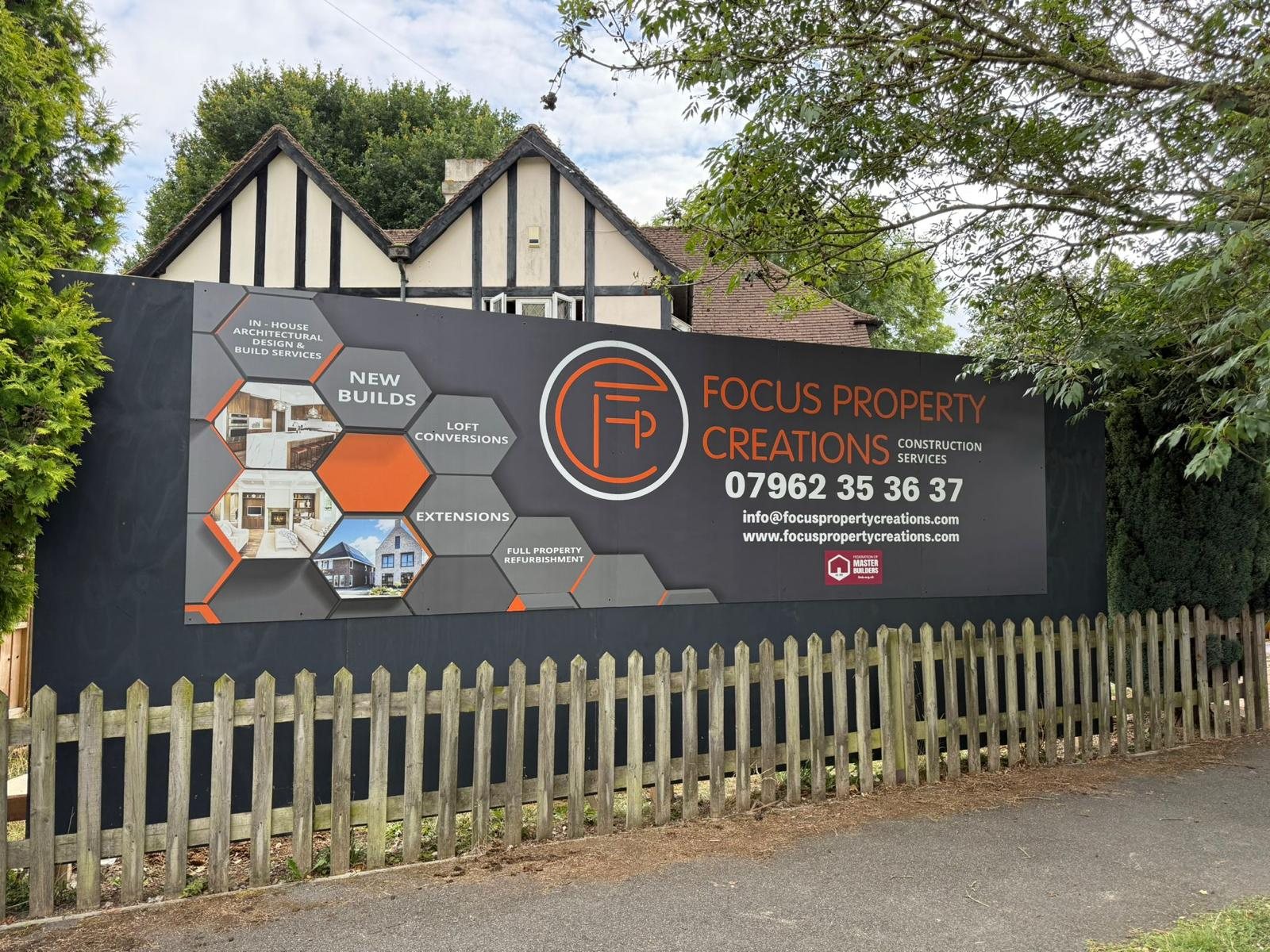 Charcoal and orange Focus Property Creations hoarding with a hexagon design showing new builds, extensions and loft conversions