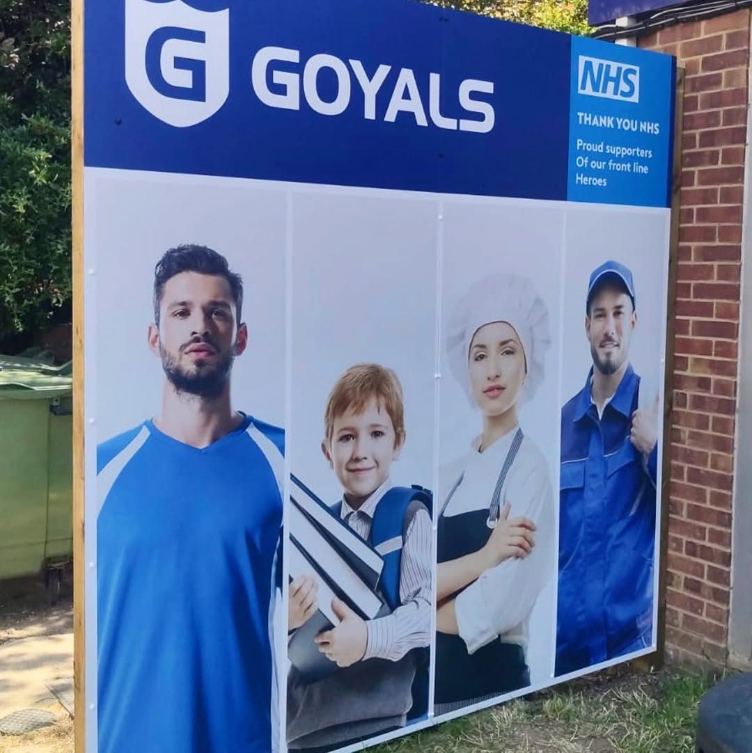 Printed Goyals hoarding board used as a retail sign outside a shop, with a blue header, a Thank you NHS panel and four lifestyle portraits