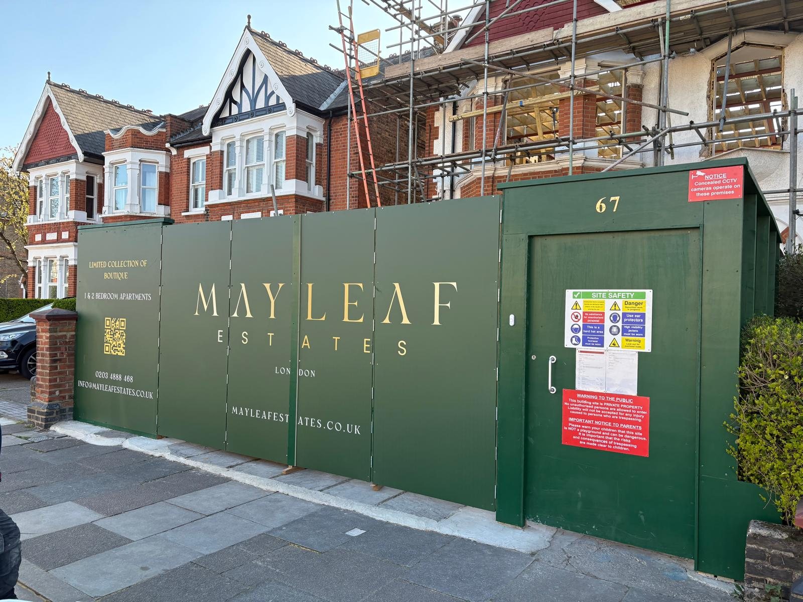 Dark green Mayleaf Estates development hoarding with gold lettering