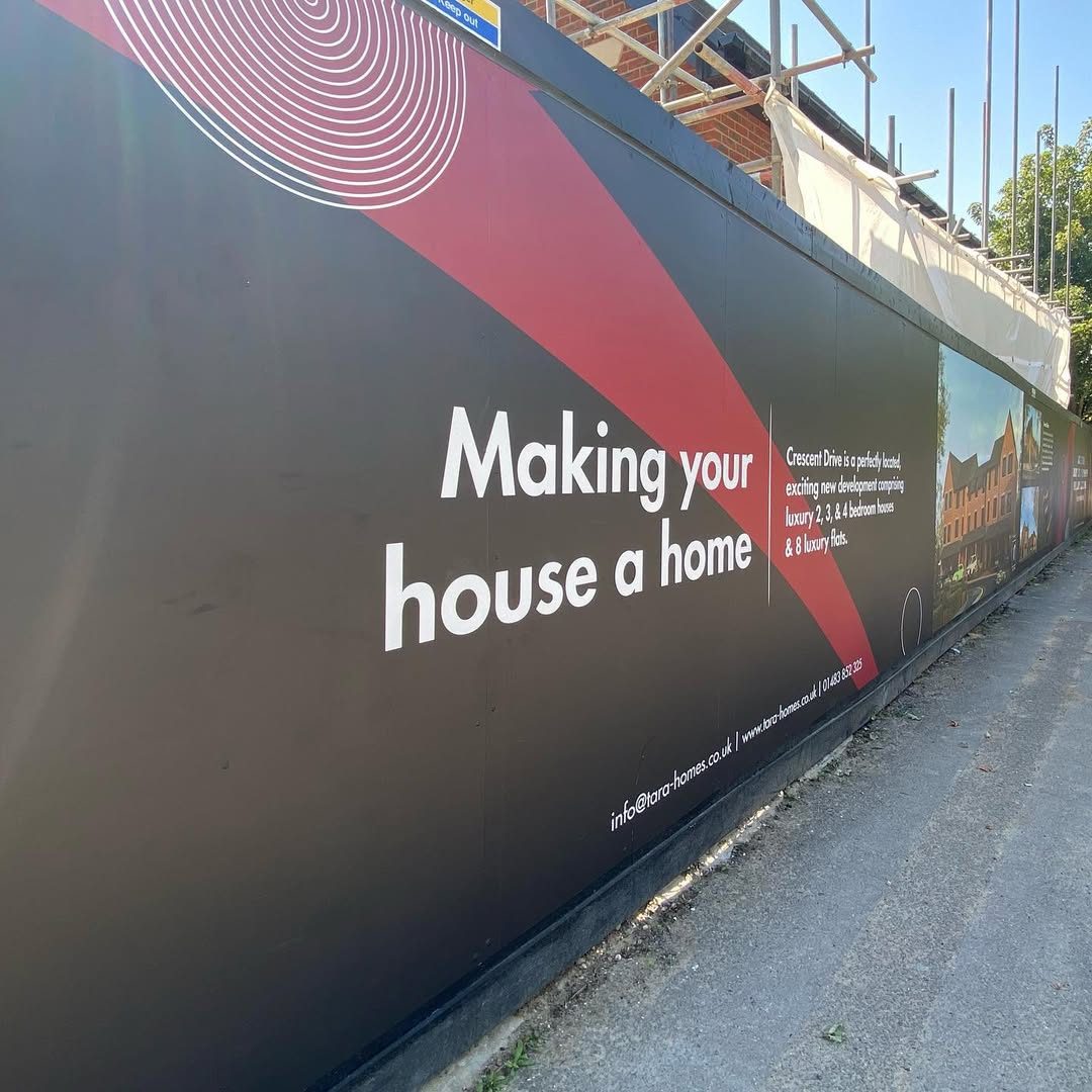 Tara Homes Crescent Drive site hoarding in charcoal and red reading Making your house a home, running along a pavement beside scaffolding