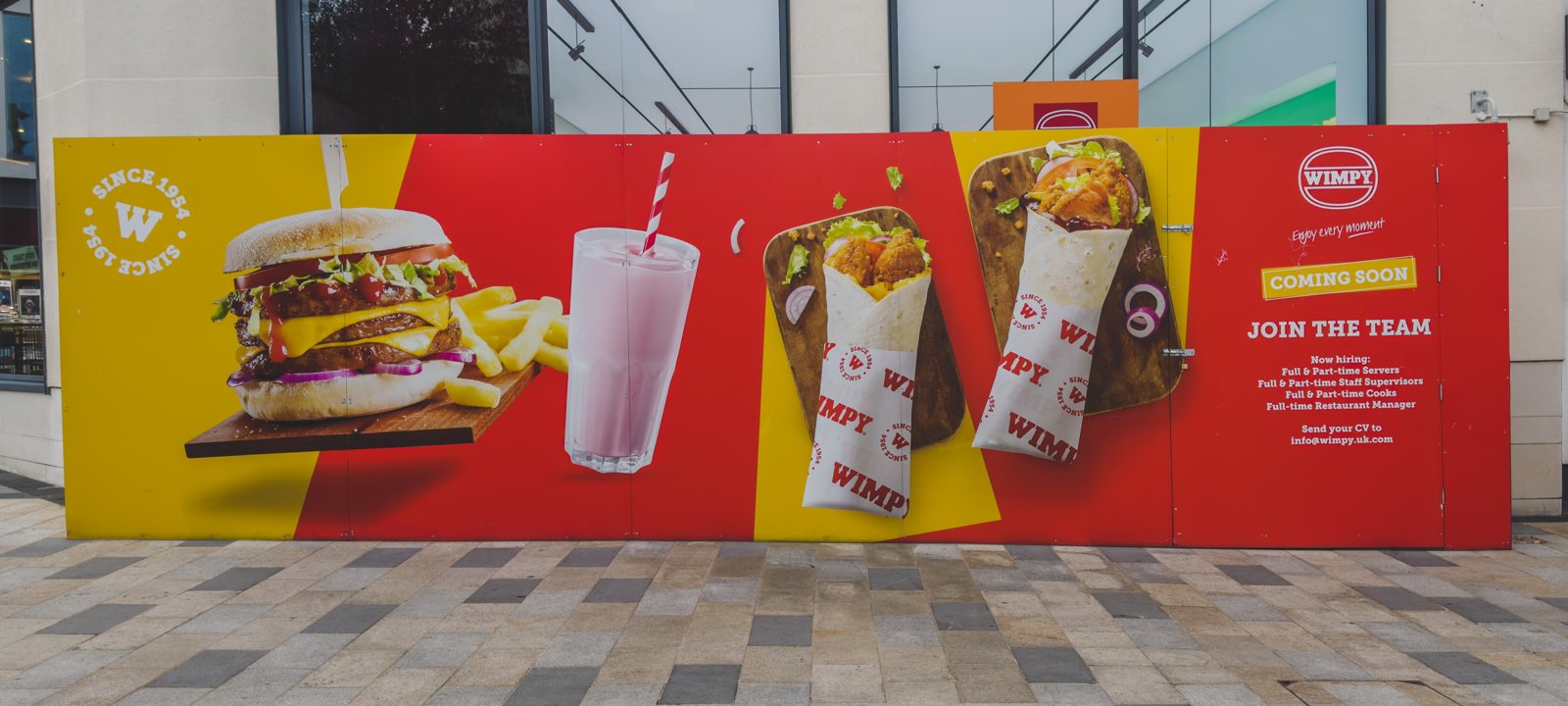 WIMPY restaurant coming soon hoarding with a giant burger, milkshake and wraps on bold red and yellow panels