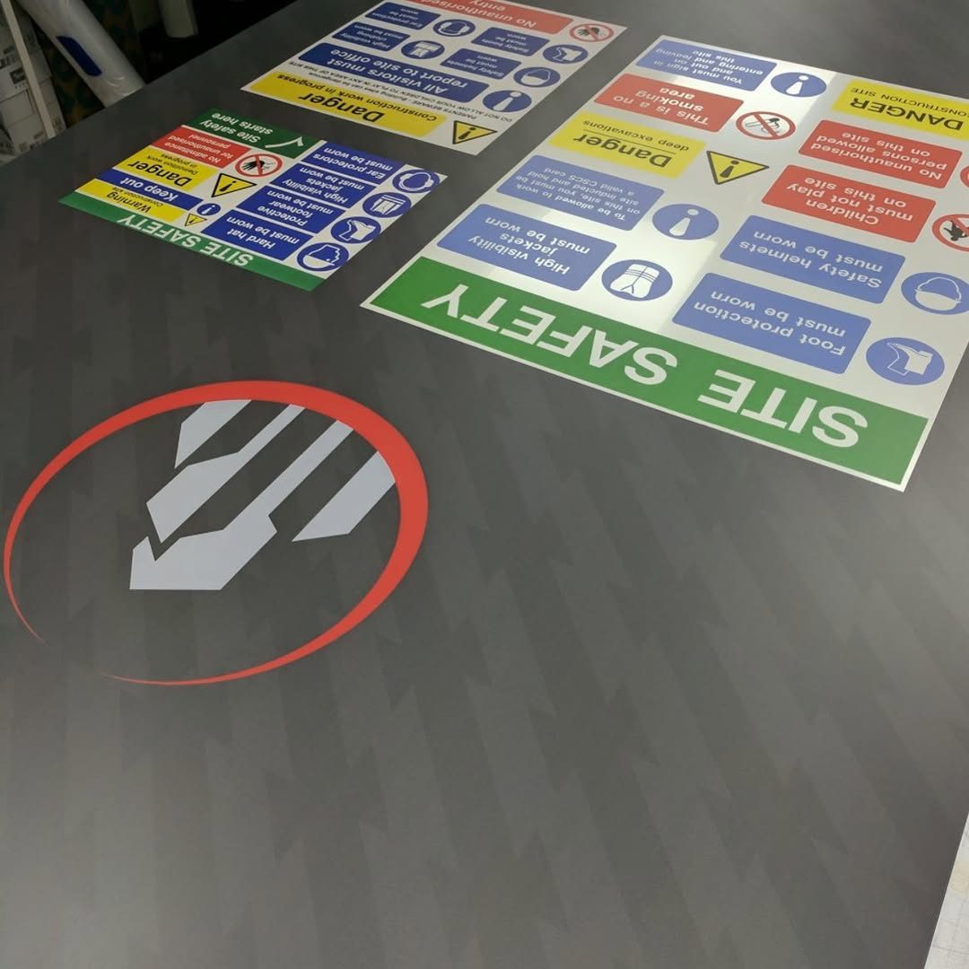 Freshly printed site safety signs on white ACM sheets lying on the bed of the Fuji UV flatbed printer