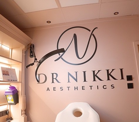 Black cut to shape Dr Nikki Aesthetics logo and lettering fixed to a blush pink clinic wall