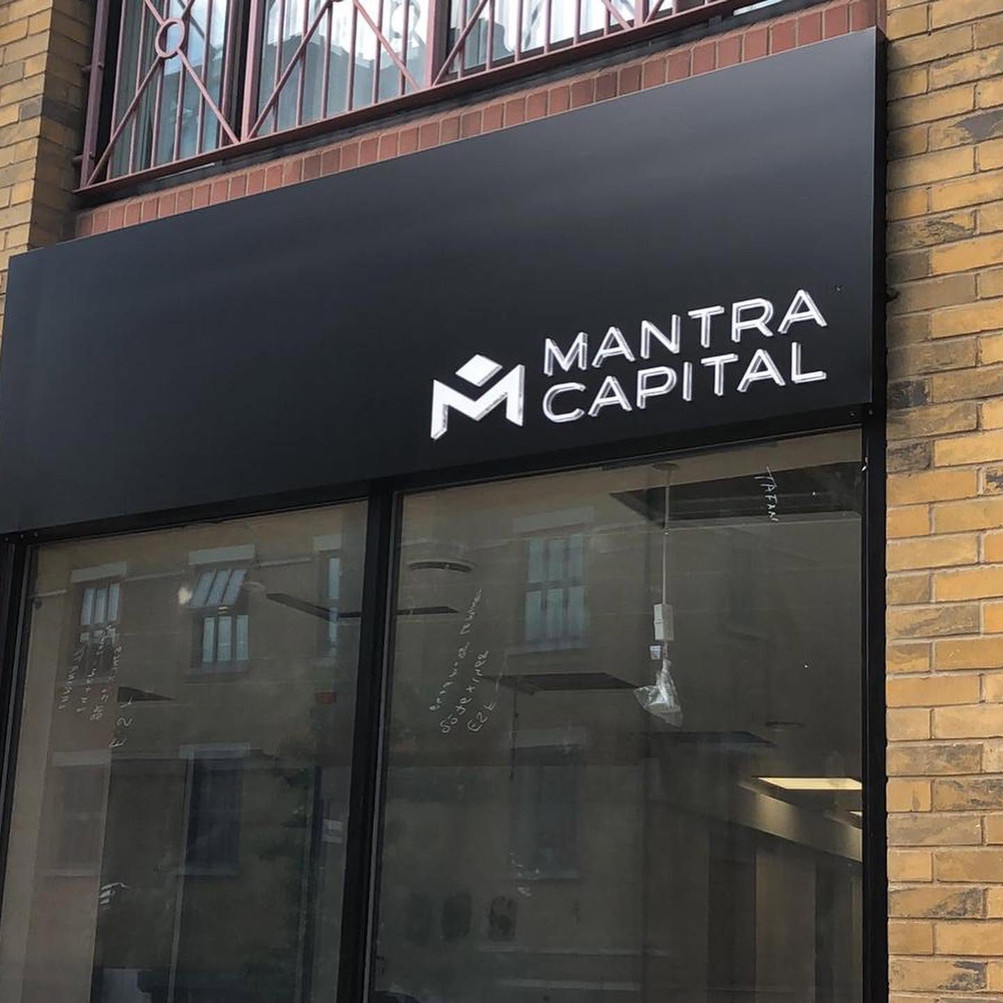 Mantra Capital shop fascia with raised clear acrylic logo and lettering mounted on a matt black ACM back board above a glazed shopfront