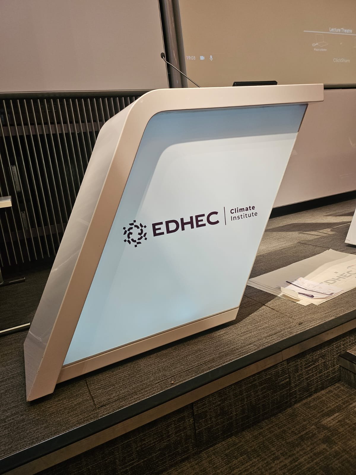 Angled conference lectern wrapped in white vinyl with the EDHEC Climate Institute logo