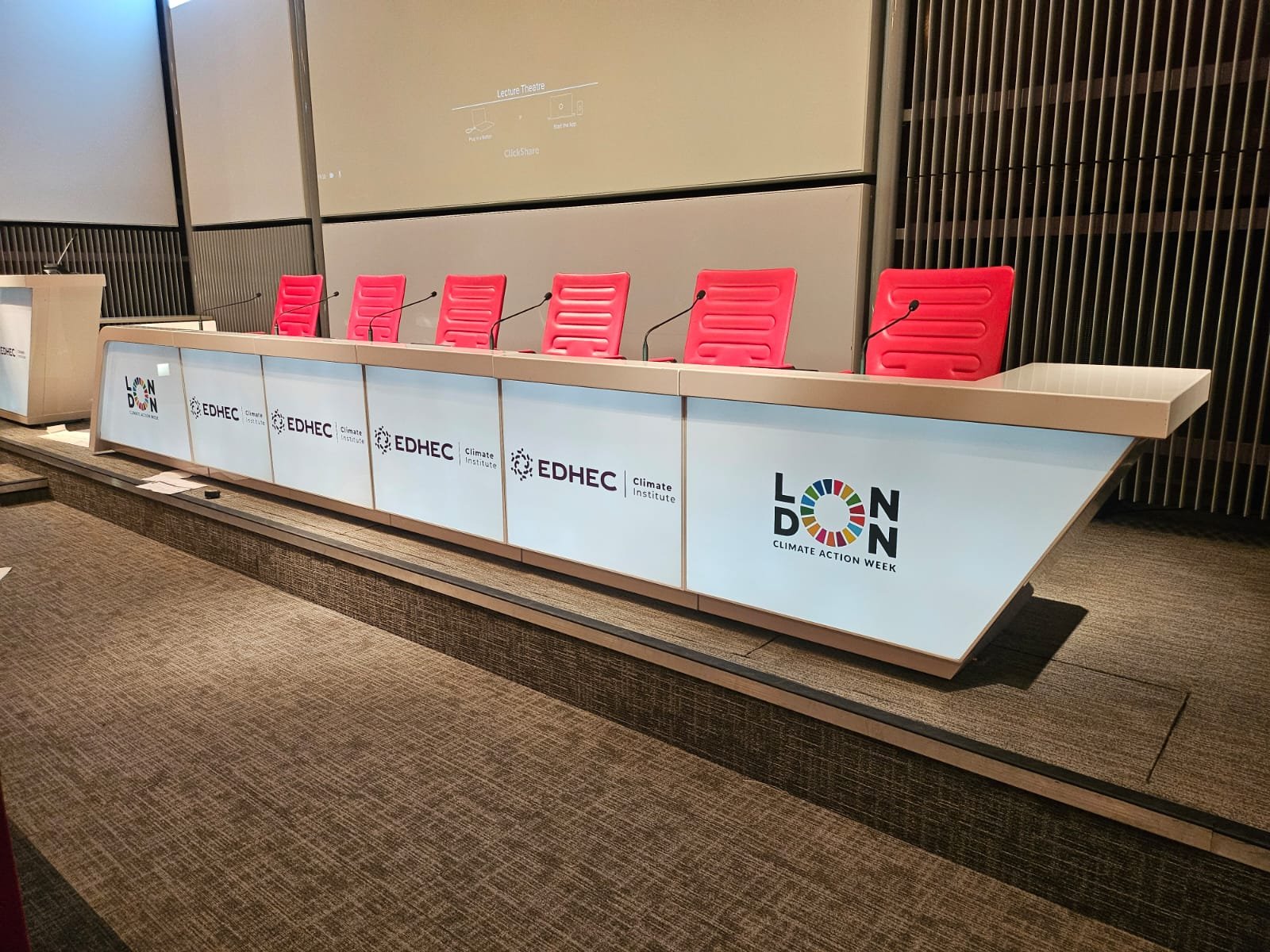 Panel desk wrapped in printed vinyl with EDHEC Climate Institute and London Climate Action Week logos in a lecture theatre