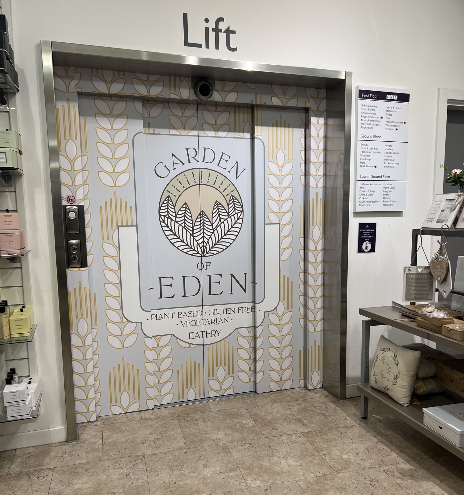 Lift doors in Daniels Windsor wrapped in printed vinyl with a golden wheat pattern and the Garden of Eden plant based eatery logo