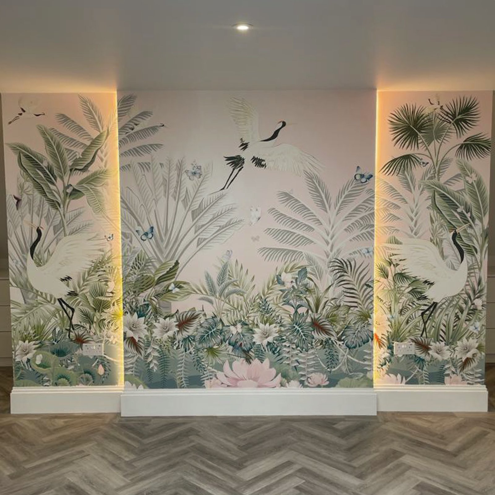 Custom botanical wallpaper mural with white cranes, palms, lotus flowers and butterflies on a soft blush wall with LED lit recesses