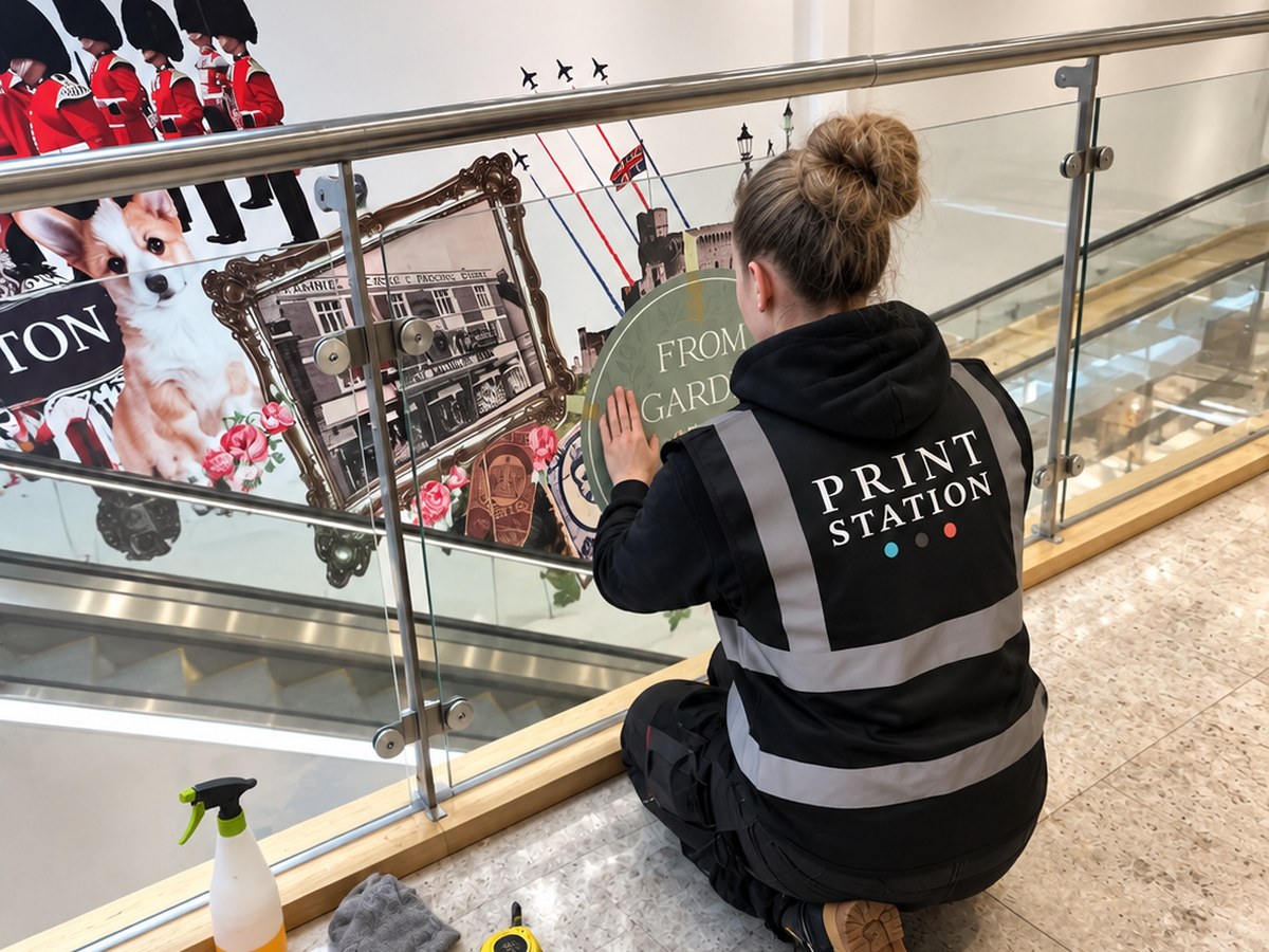 Print Station installer fitting a printed graphic to a glass balustrade in a shopping centre