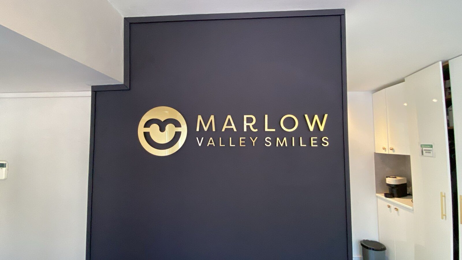 Floating matt gold acrylic 3D logo and lettering on the Marlow Valley Smiles blue canvas feature wall