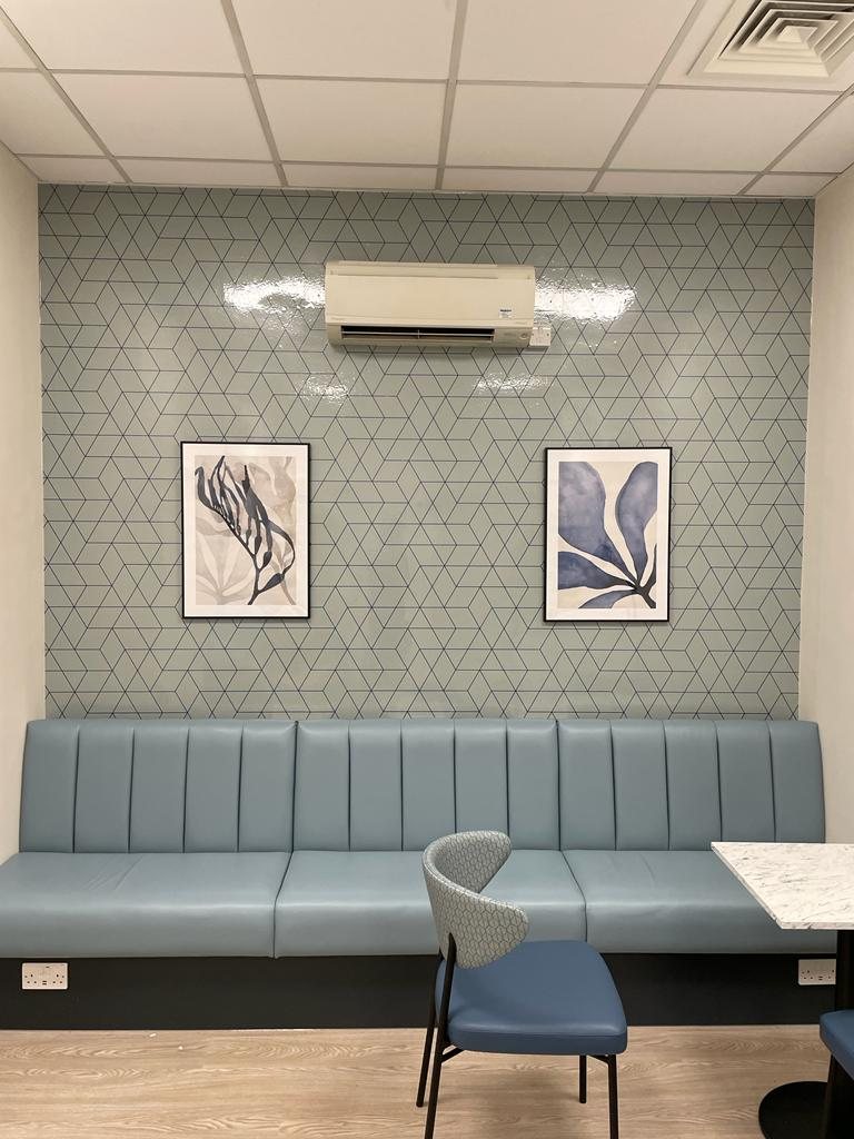 NHS staff breakout room with a printed geometric antibacterial wallpaper behind blue banquette seating