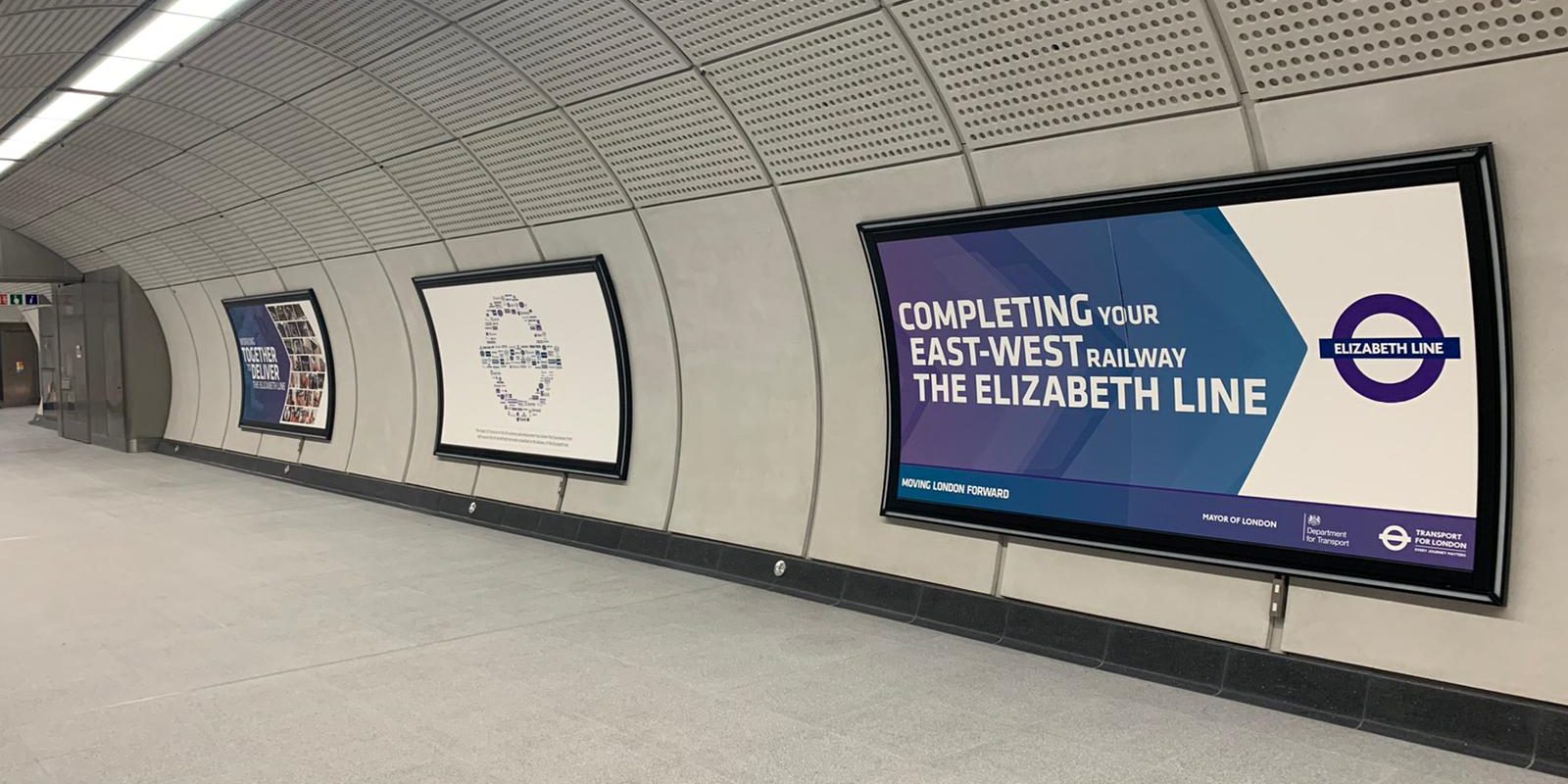Elizabeth line launch posters in curved frames along a new platform tunnel