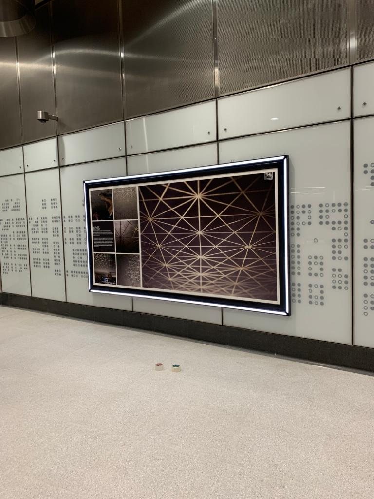 A poster in an illuminated frame on a station concourse